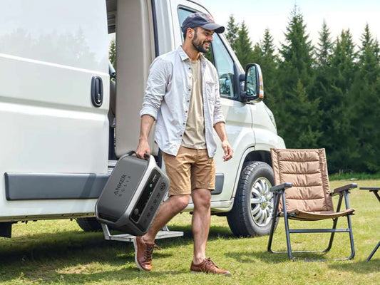 Man carrying a portable power station beside an RV